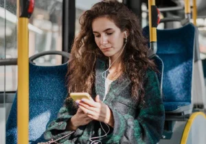 mulher branca com cabelo longo sentada no ônibus e mexendo no celular